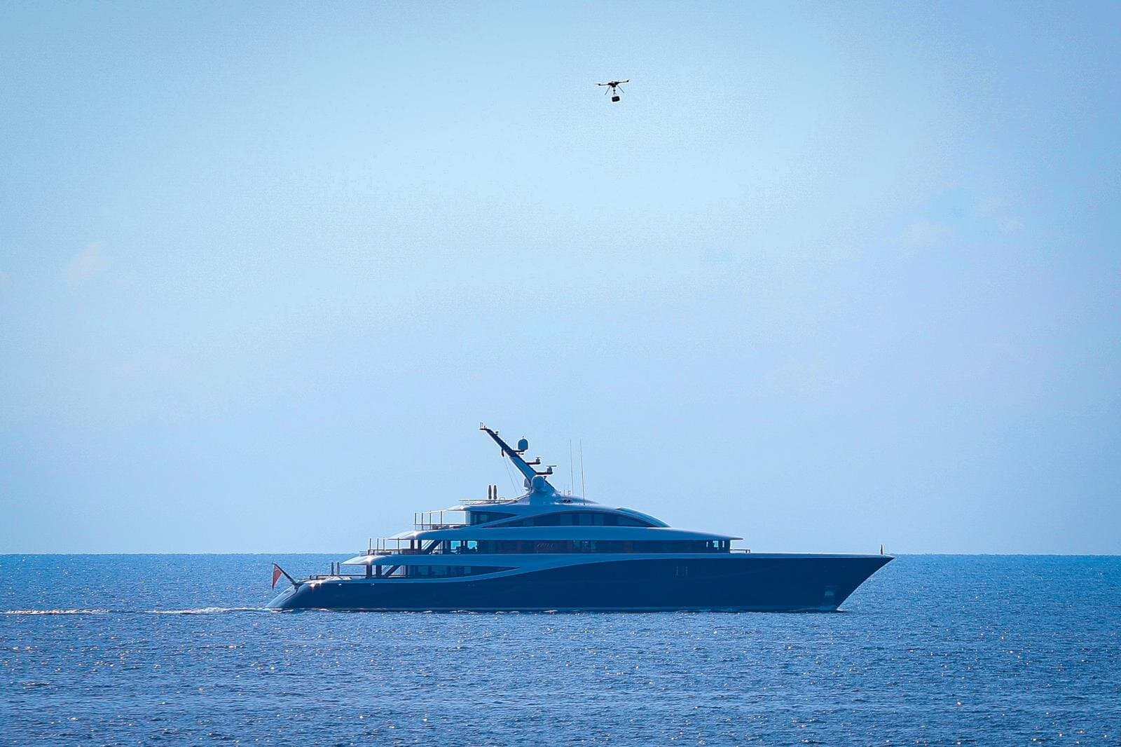 Delivery drone lowering a parcel to a superyacht at anchor